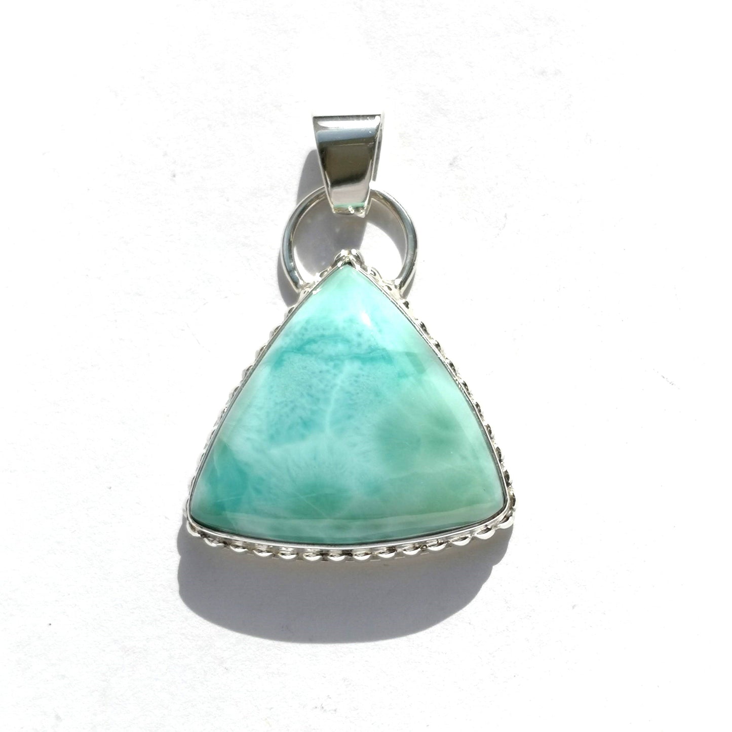 colgante realizado artesanalmente en plata de ley con un larimar triangular y un diseño en el borde con bolitas